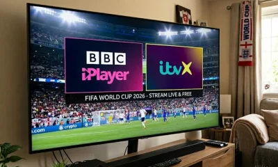 A smart TV screen in a living room displaying a split graphic of the BBC iPlayer and ITVX logos over a live World Cup 2026 football match.